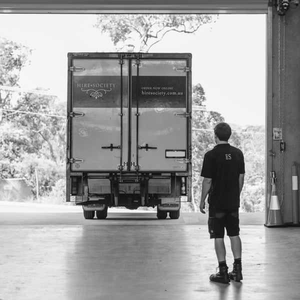 Man standing in front of a large moving truck with 'Hire Society' branding.
